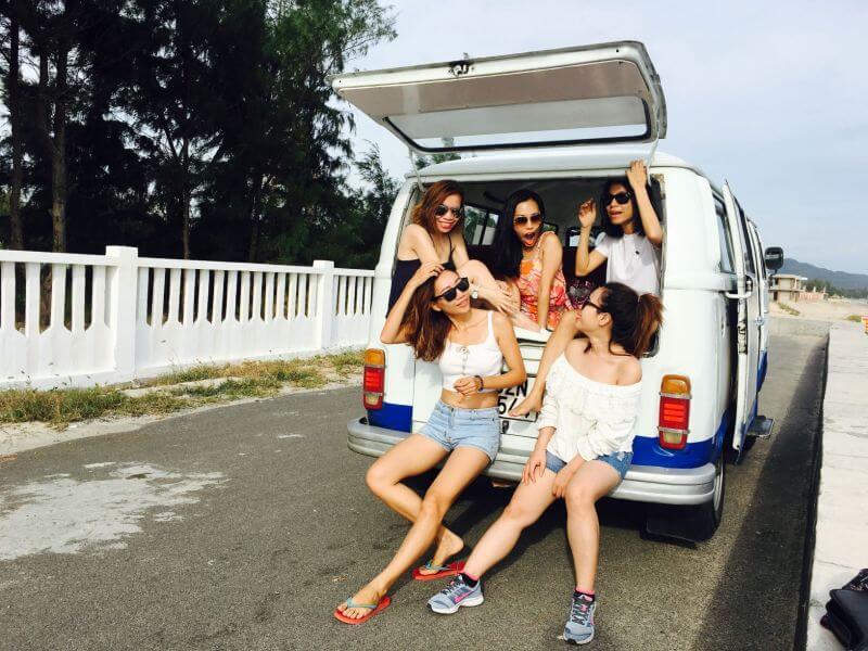 meninas em kombi sentadas no porta-malas durante uma viagem em grupo