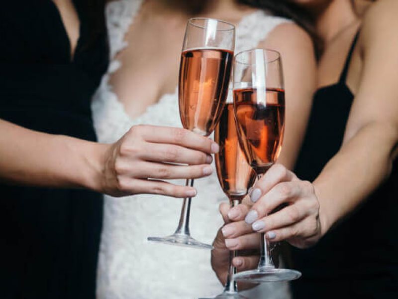 Imagem de três pessoas brindando com taças de champagne