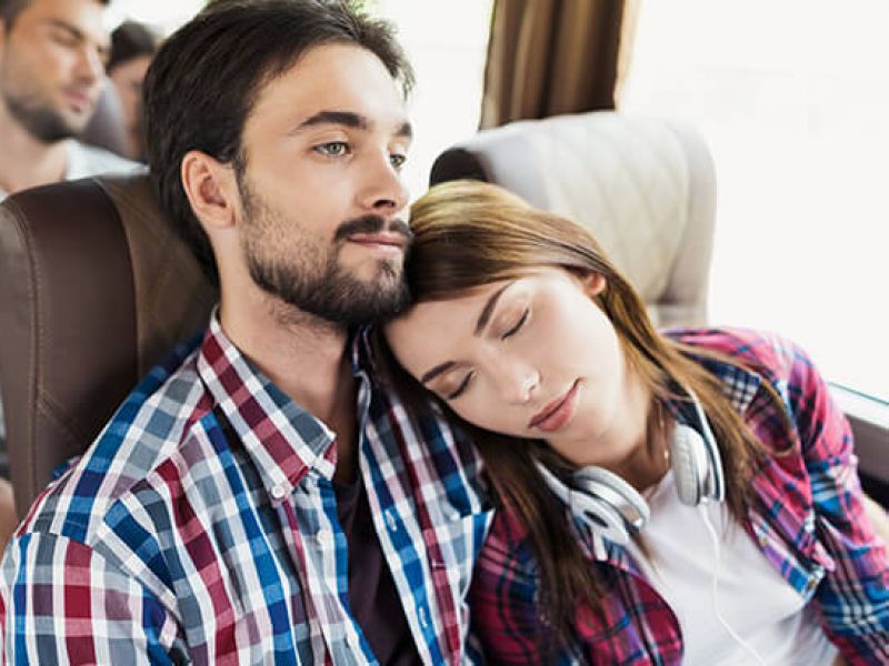 Imagem de um homem e uma mulher viajando juntos em um ônibus