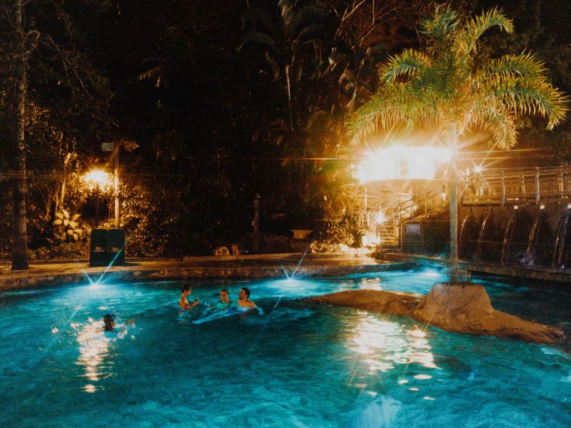 Quatro pessoas relaxando em uma das piscinas do Rio Quente Resorts, durante a noite, com a piscina iluminada