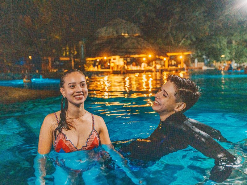 Duas pessoas sentadas em uma das piscinas termais de Rio Quente durante a noite