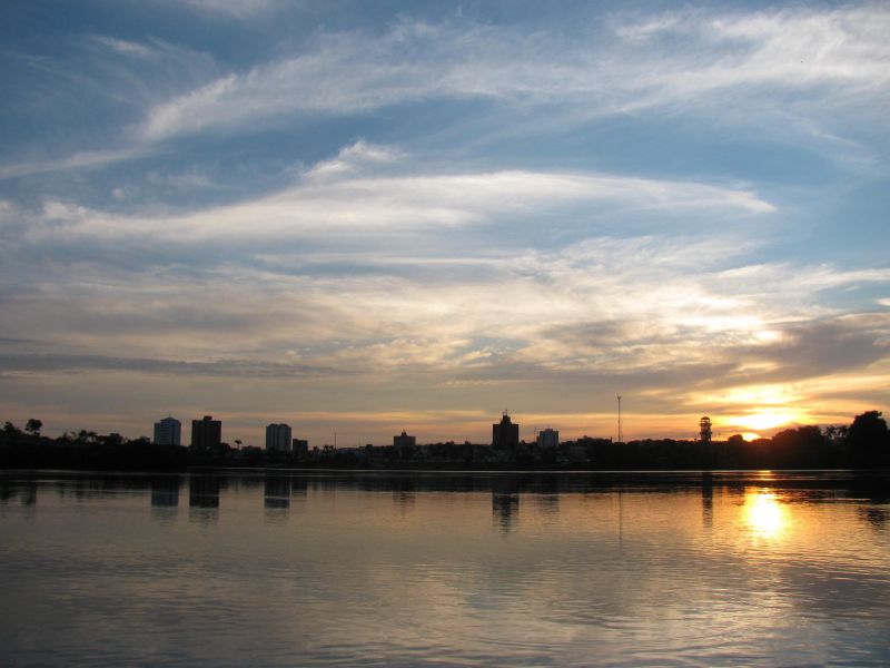 Foto panorâmica da cidade de Itumbiara, em Goiás. Em primeiro plano está o rio Parnaíba e a cidade ao fundo, com o sol se pondo