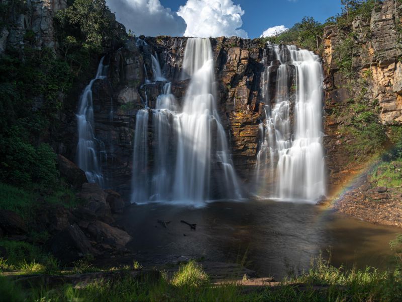 Cachoeira de Salto Corumbá, cercada de um paredão de pedra com alguma vegetação.