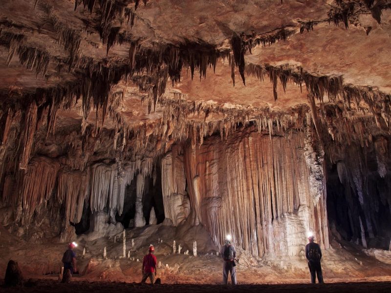 Quatro pessoas de costas dentro do complexo de cavernas de Terra Ronca, admirando as formações rochosas